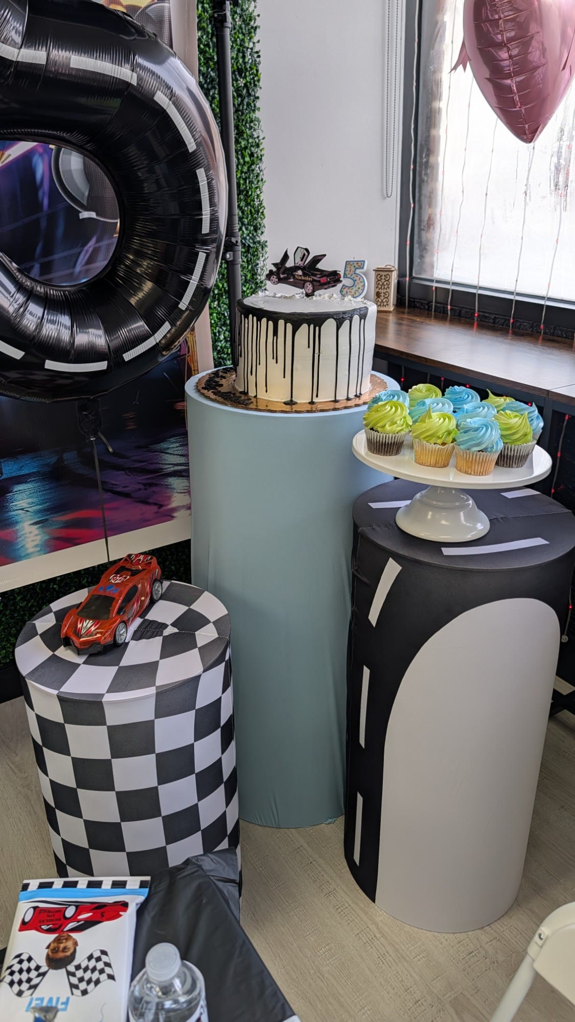 Race car birthday cake and cupcakes set up on pedestals at JJ's